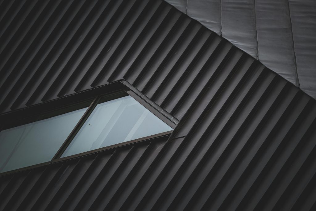 A sleek metal rooftop with a unique window, showcasing modern architectural style and geometric patterns.