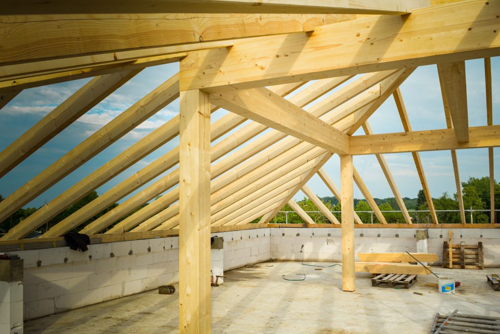 vegetative-roof Unfinished construction site with a focus on wooden roof trusses under a clear sky.